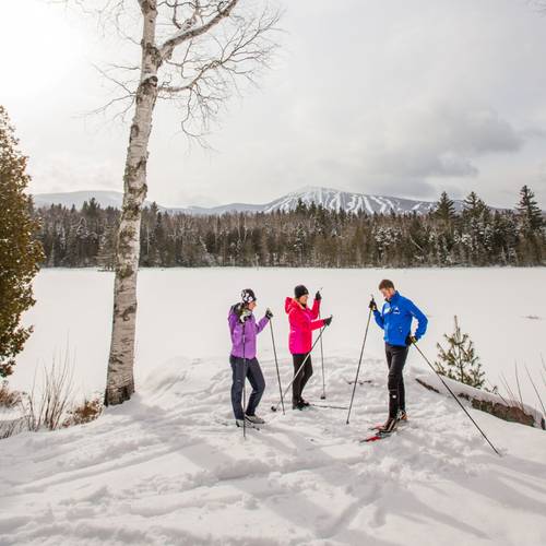 Three cross country skiers chatting with Sugarloaf in the background