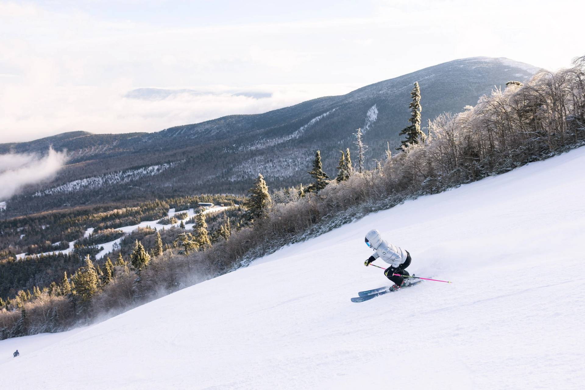 Skier making soft turns down Sluice with views of Burnt Mt. and Whiffletree