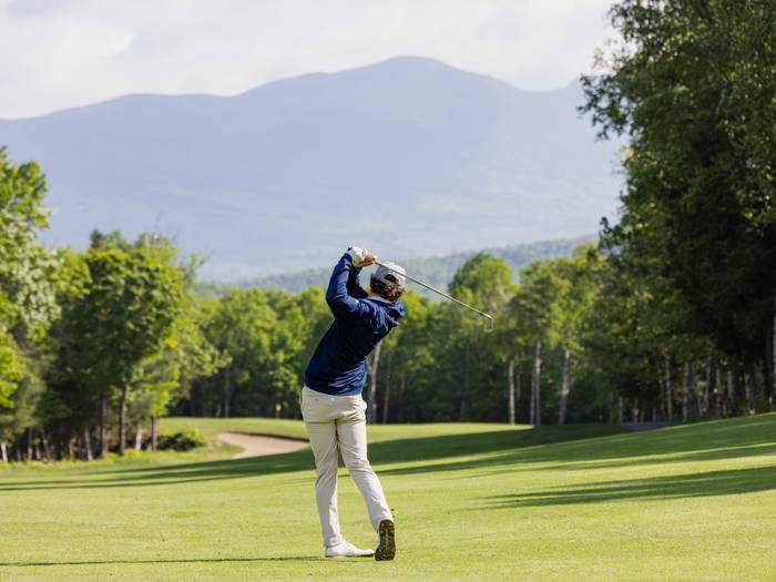 Golfer swinging on course
