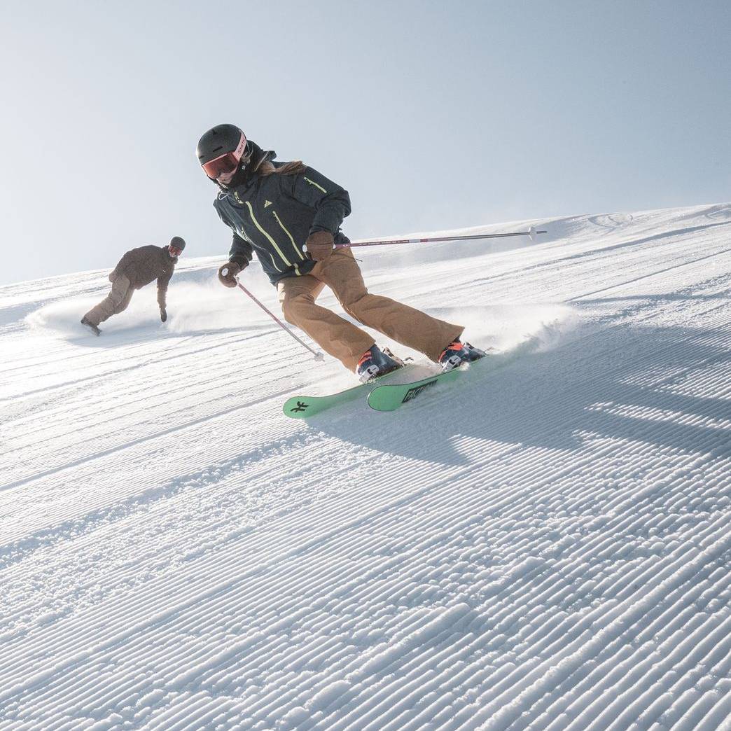 Skier and snowboarder on a groomed run