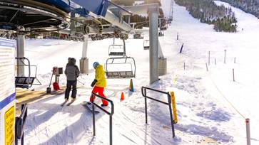 Skier and rider loading onto lift