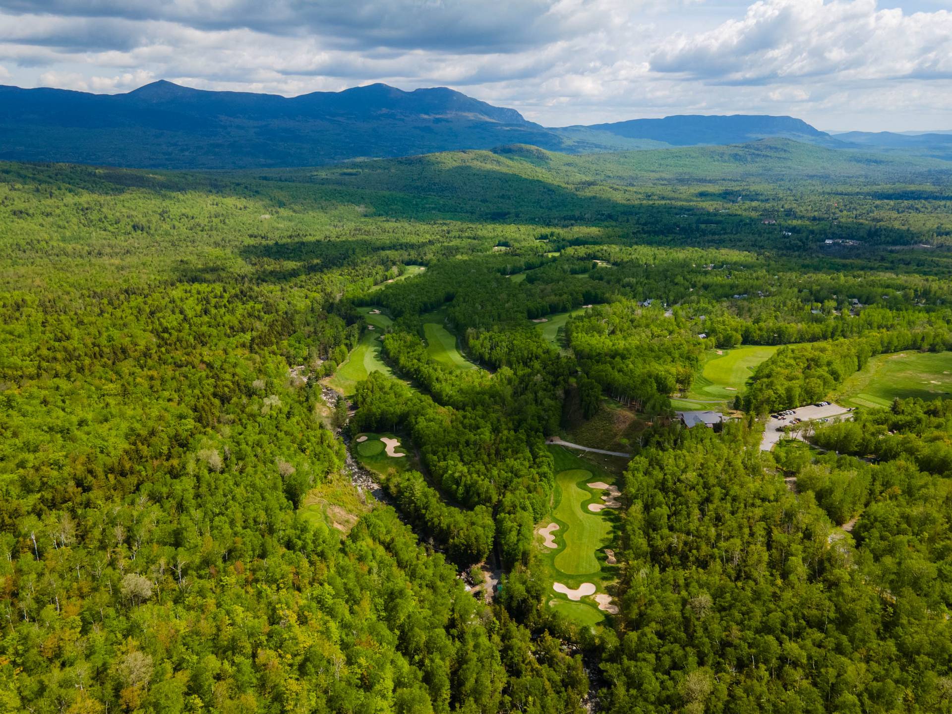 Drone shot above the Sugarloaf Golf Course showing full green colors and the Bigelow Range in the background