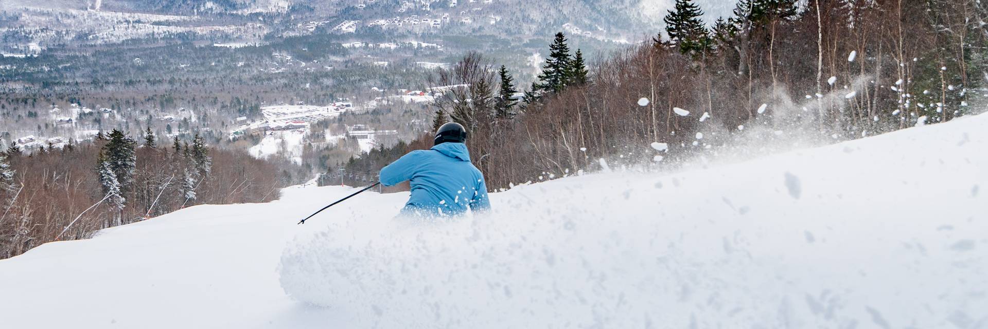 A man skiing down a trail, with snow coming up, at Sunday River.