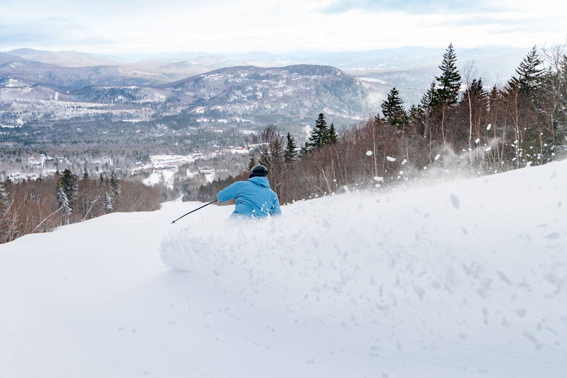 A man skiing down a trail, with snow coming up, at Sunday River.