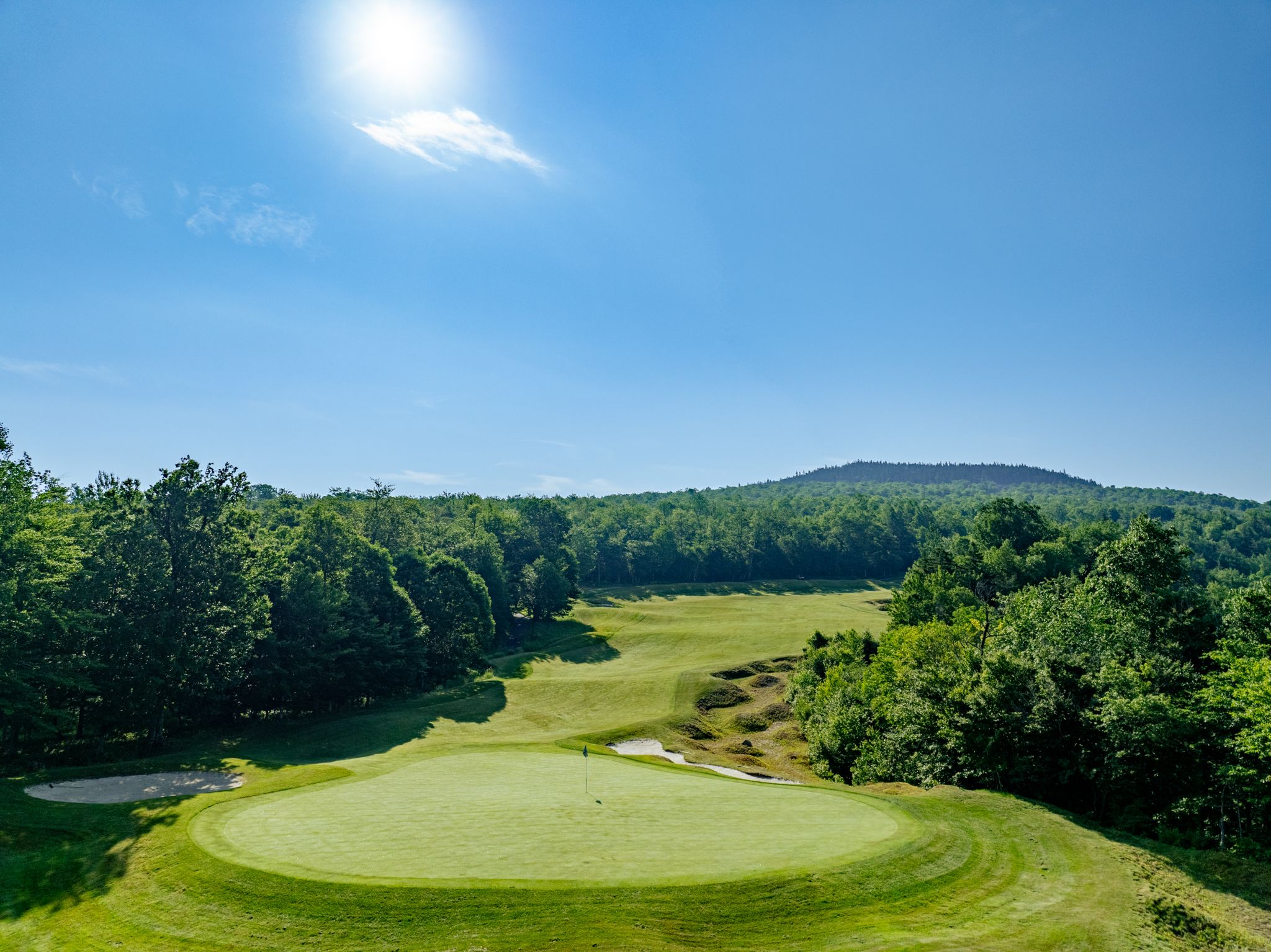 Tee box at Sunday River in the summer with blue skies and green trees.