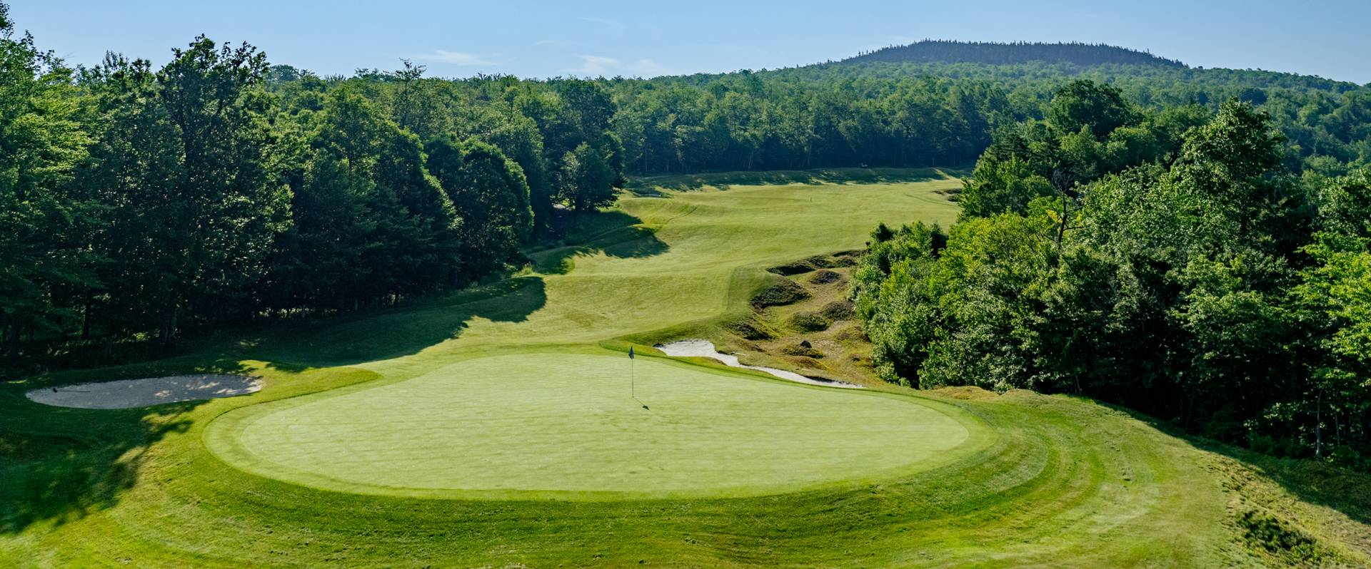 Tee box at Sunday River in the summer with blue skies and green trees.