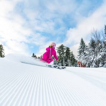 A woman skiing in a pink suite at Sunday River.
