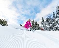 A woman skiing in a pink suite at Sunday River.