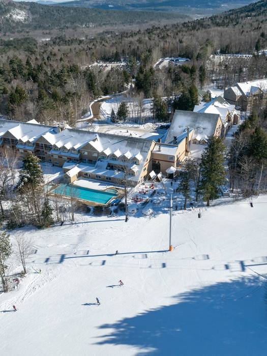 An aerial view of the Grand Summit Hotel, at Sunday River, with the pool and skiers.
