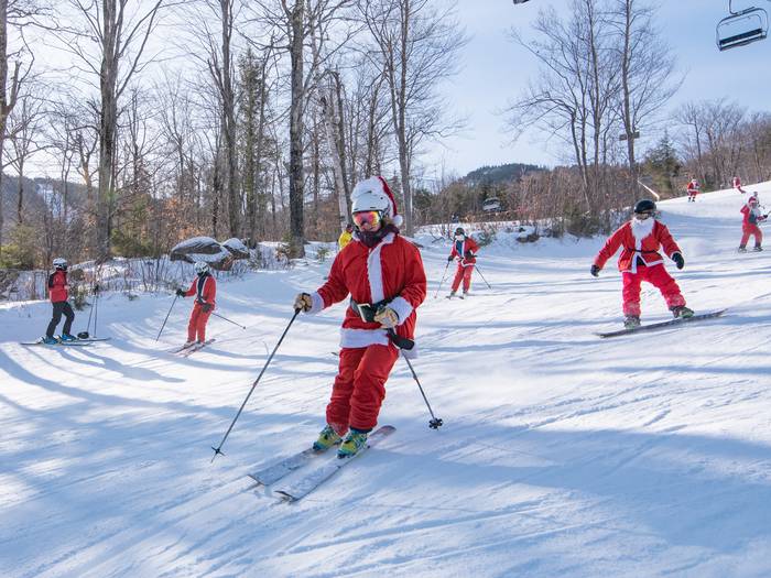 Santas skiing down a trail for Santa Sunday at Sunday River.