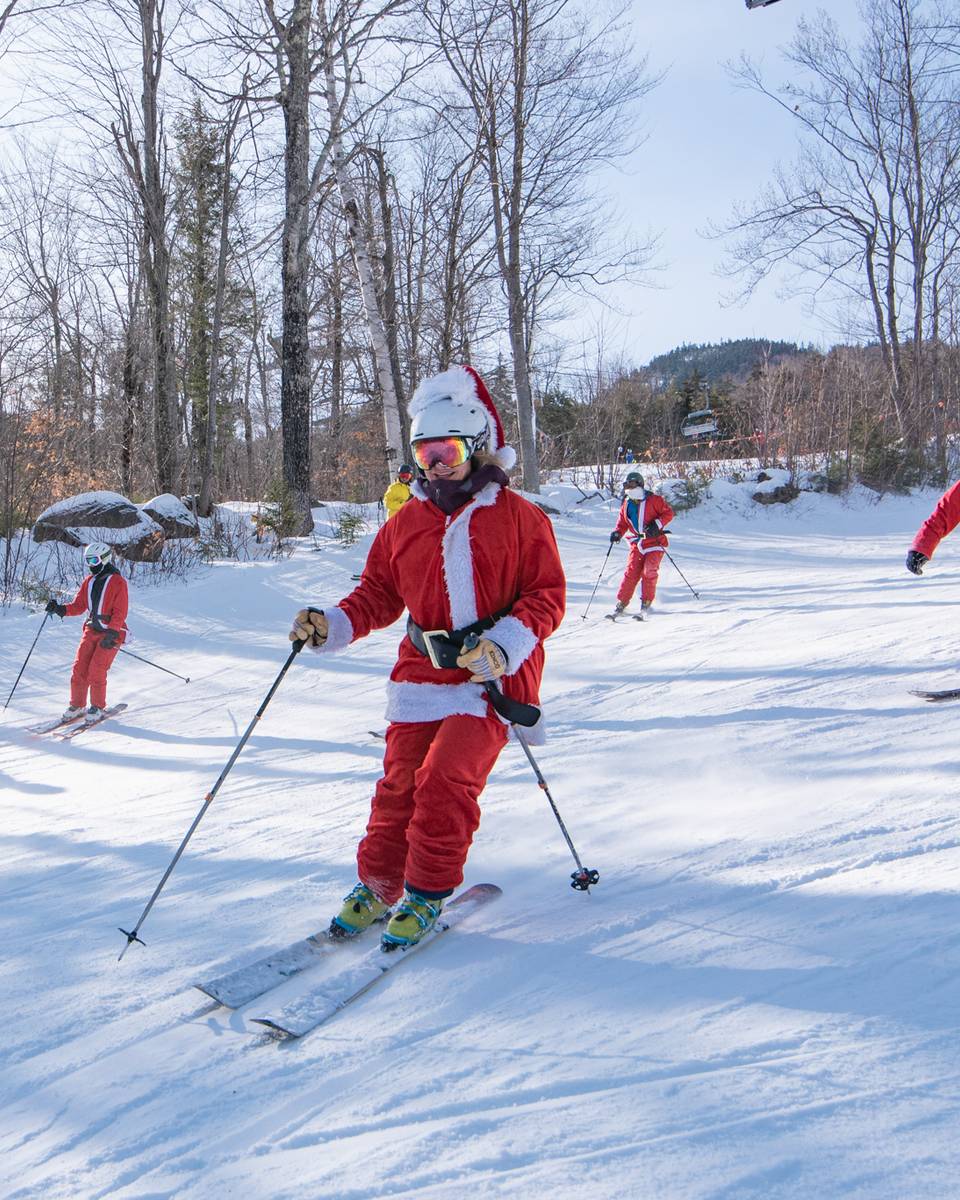 Santas skiing down a trail for Santa Sunday at Sunday River.