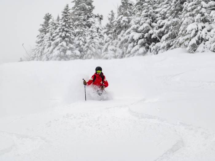 A patroller skiing in powder at Sunday River.