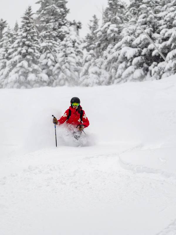 A patroller skiing in powder at Sunday River.