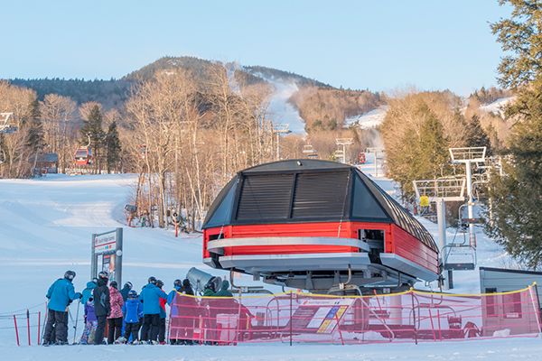 Skiers and snowboarders waiting in line at a chairlift at Sunday River.