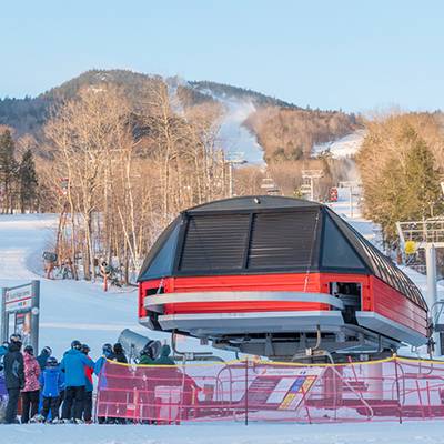 Skiers and snowboarders waiting in line at a chairlift at Sunday River.