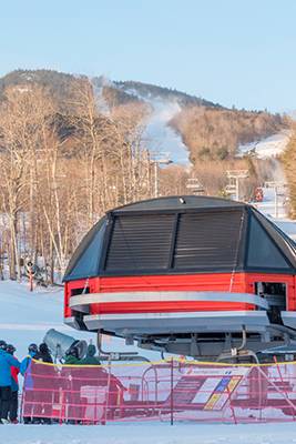 Skiers and snowboarders waiting in line at a chairlift at Sunday River.