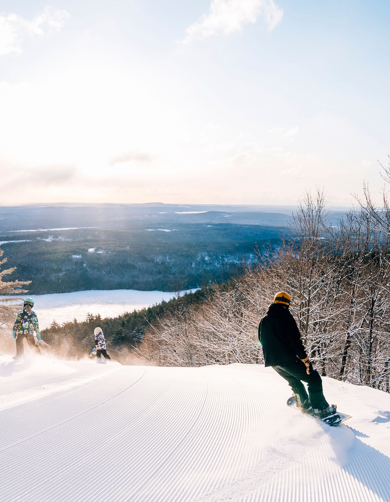 A snowboarder at the top of a run at Pleasant Mountain