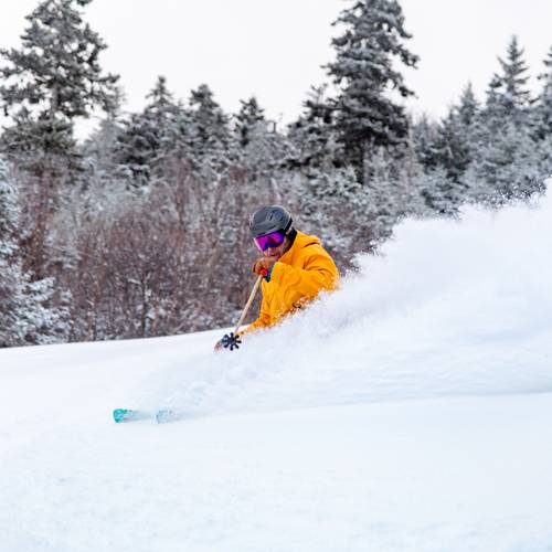 A person skiing in powder at Sunday River.