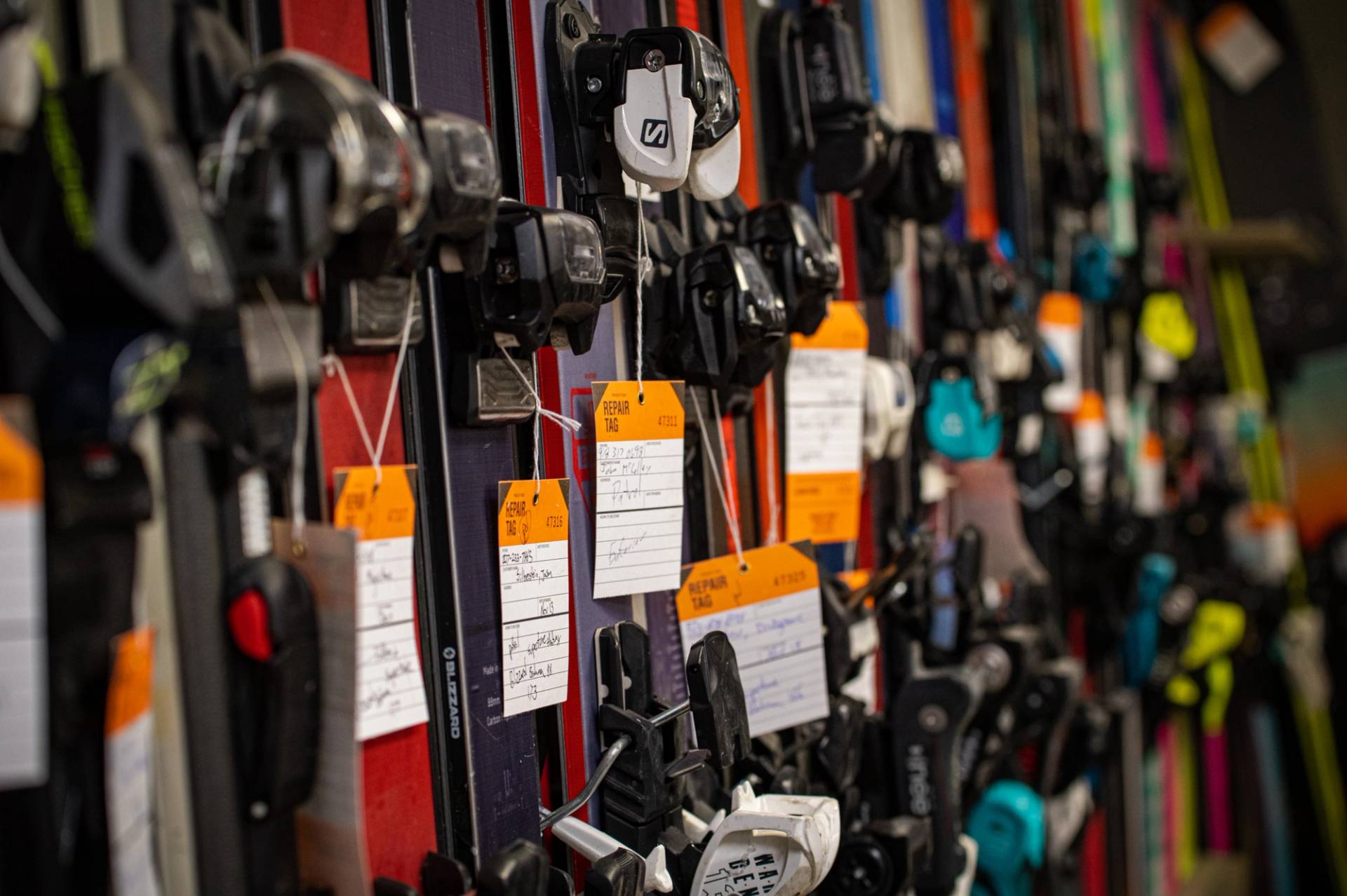 Skis in the tune shop with tags on the bindings.