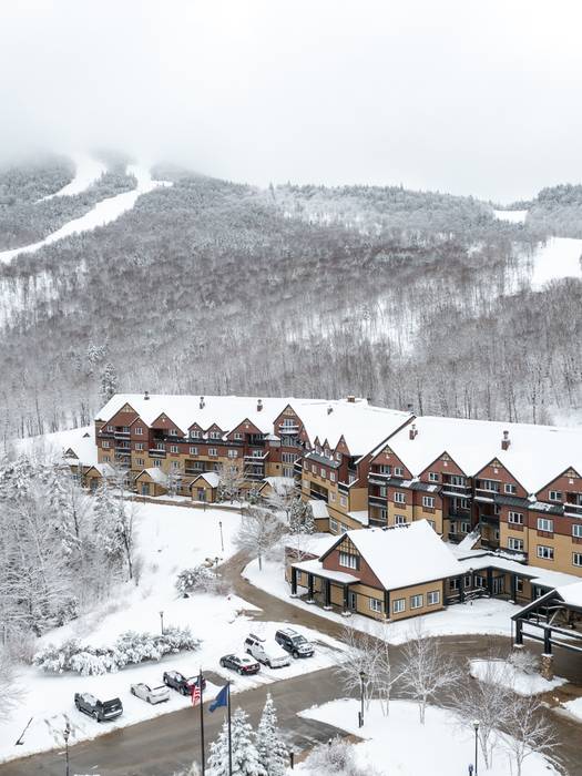 The Jordan Hotel at Sunday River with snow covering the exterior and the mountains.