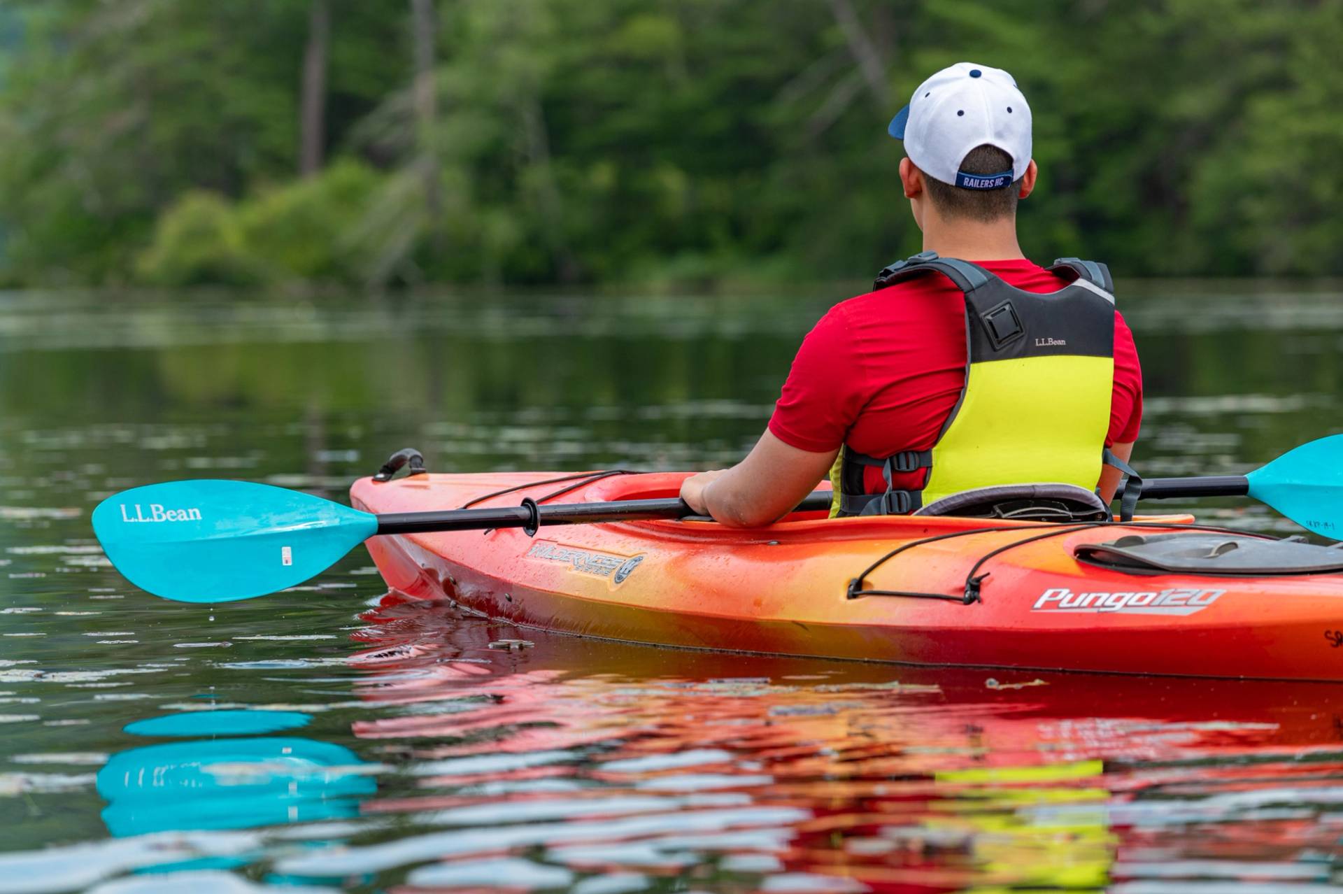 A man sitting in a kayak on a lake in Maine.