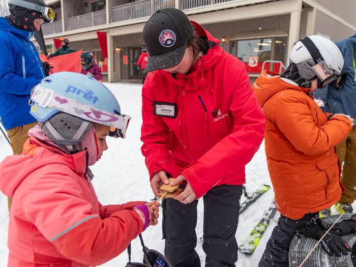 A team member from Sunday River helping a kid make a smore.