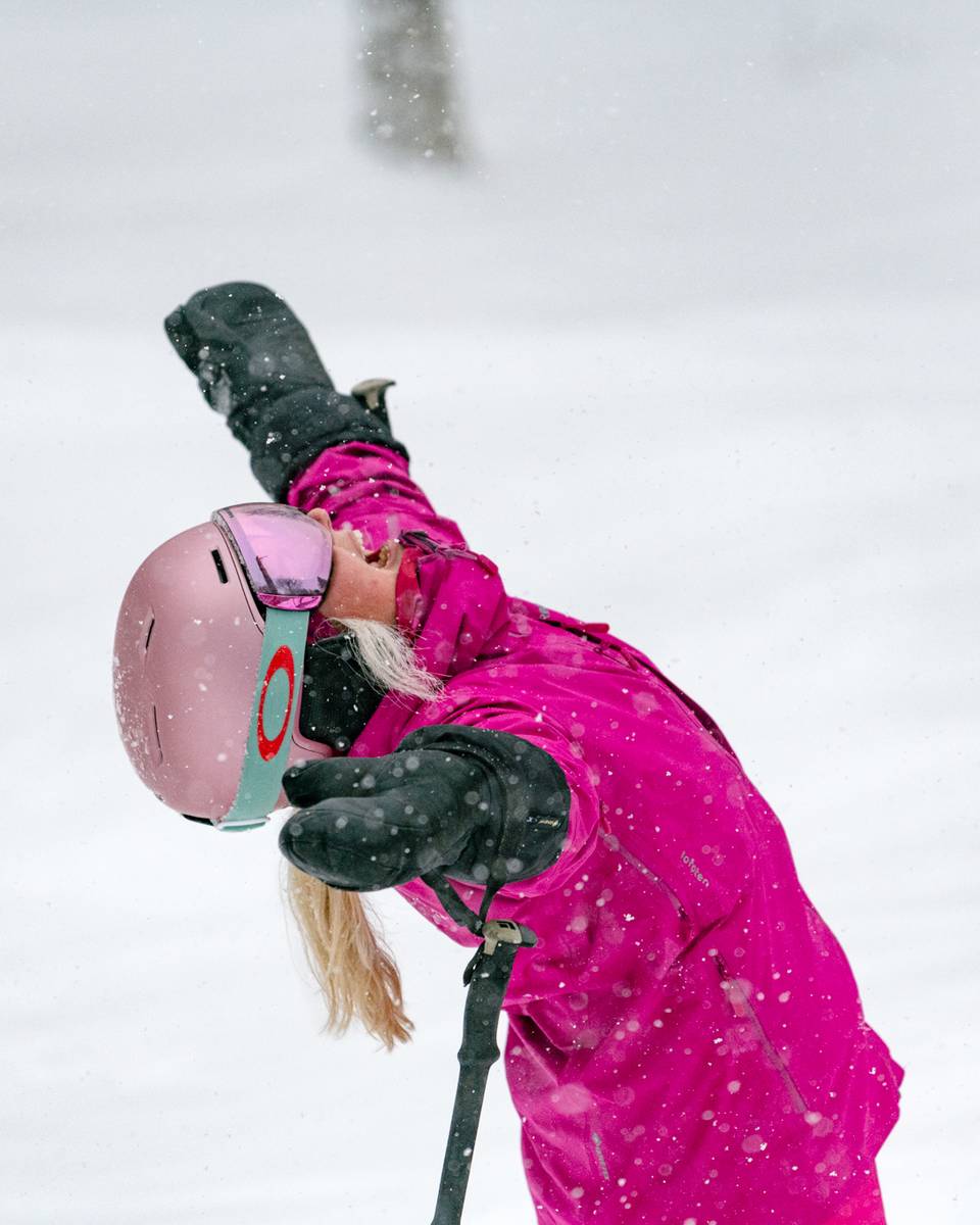 A woman in a pink snow suite happy about snow at Sunday River.