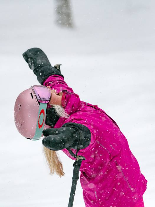 A woman in a pink snow suite happy about snow at Sunday River.