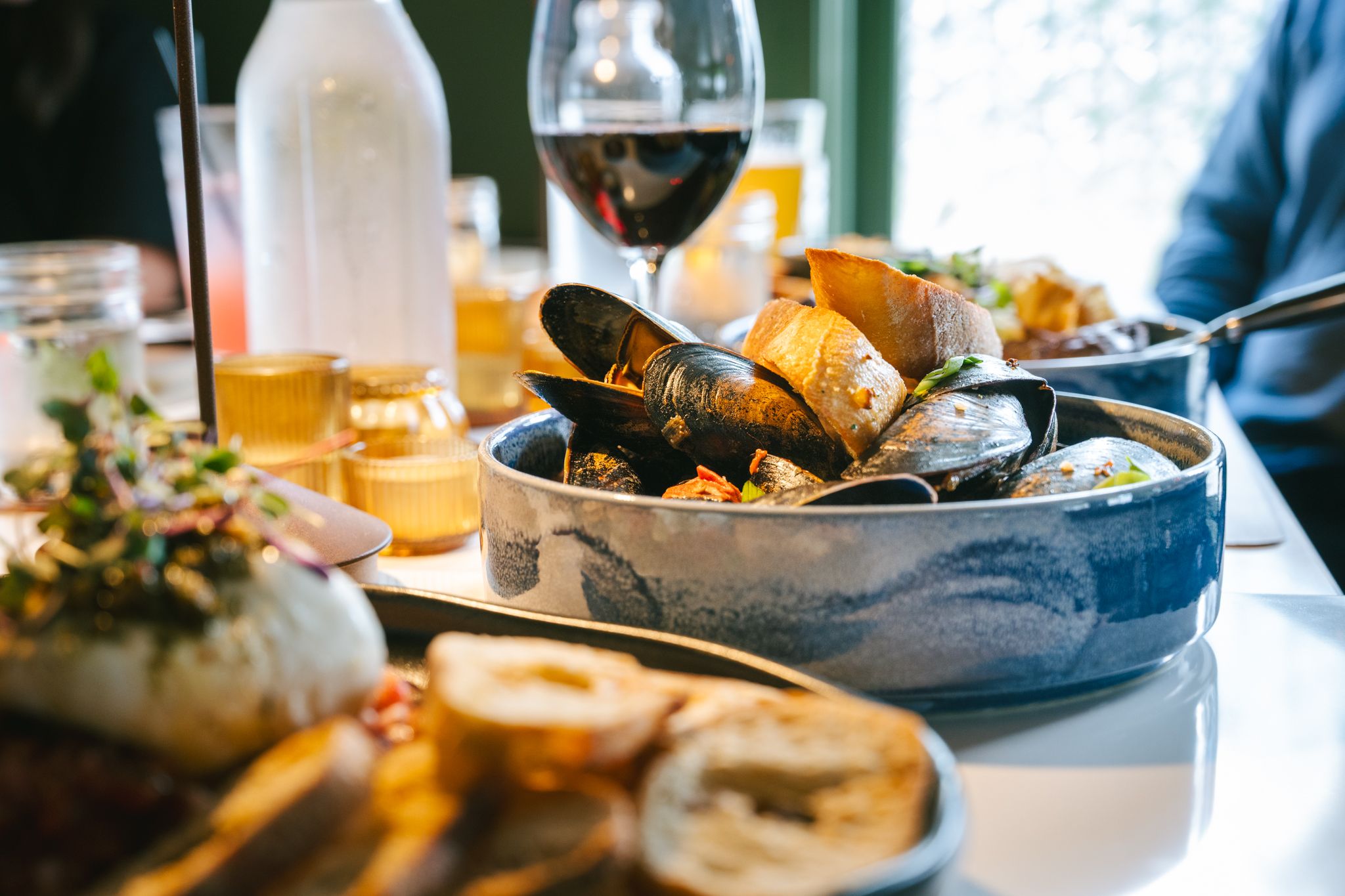 A bowl of mussels and bread on the table.