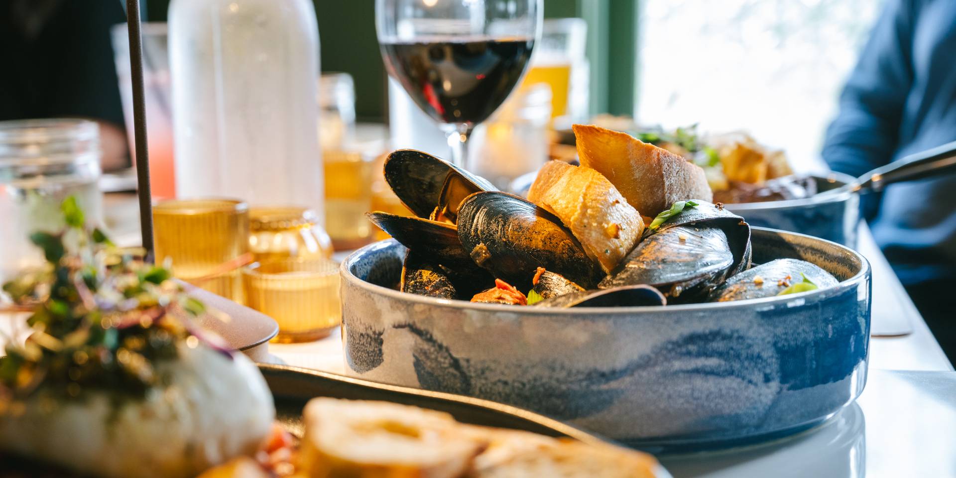 A bowl of mussels and bread on the table.