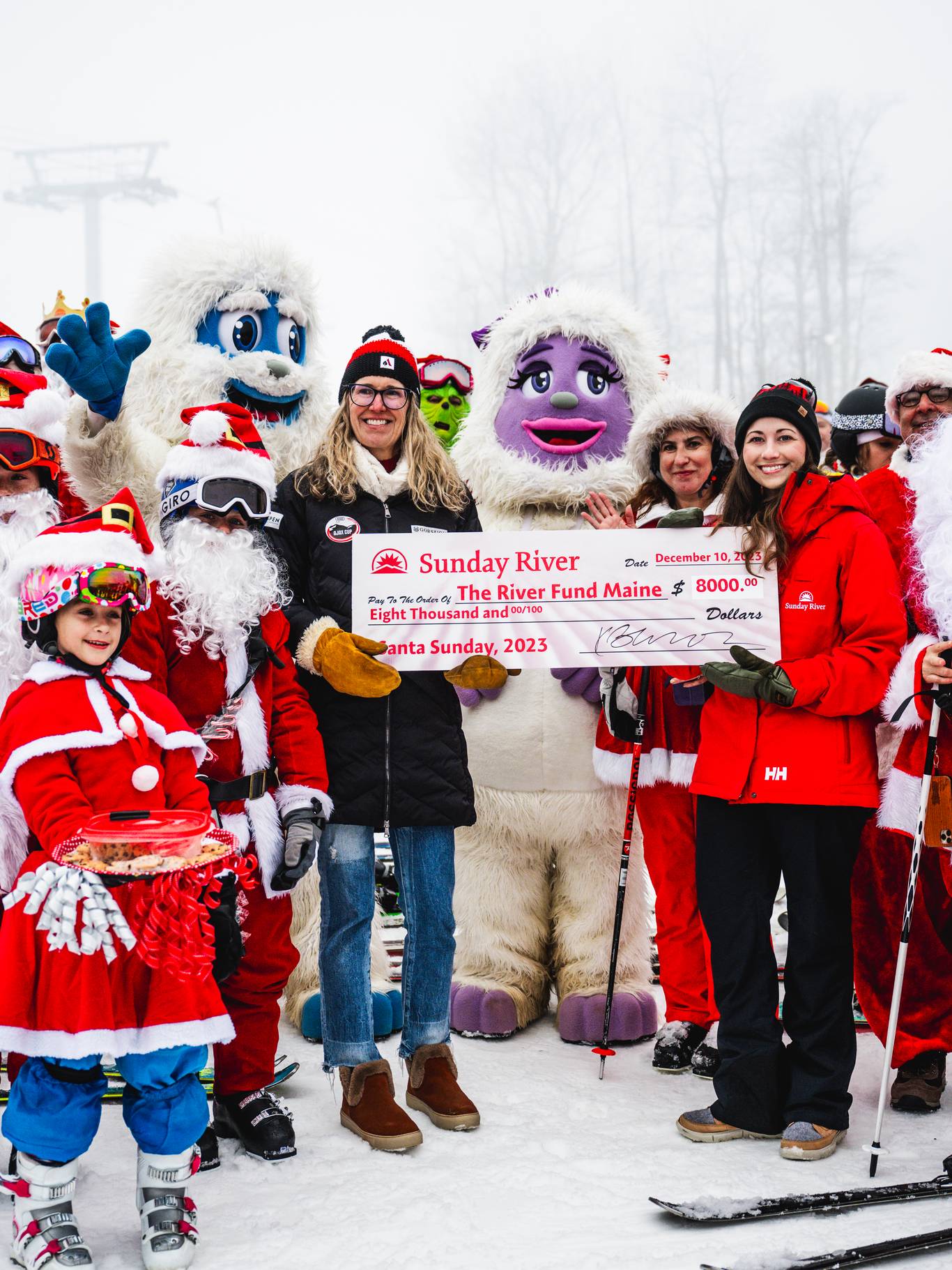 Skiers dressed as Santa during Sunday River's Santa Sunday, presenting a check to The River Fund Maine.