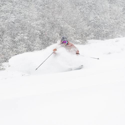 A man skiing in powder at Sunday River in March.