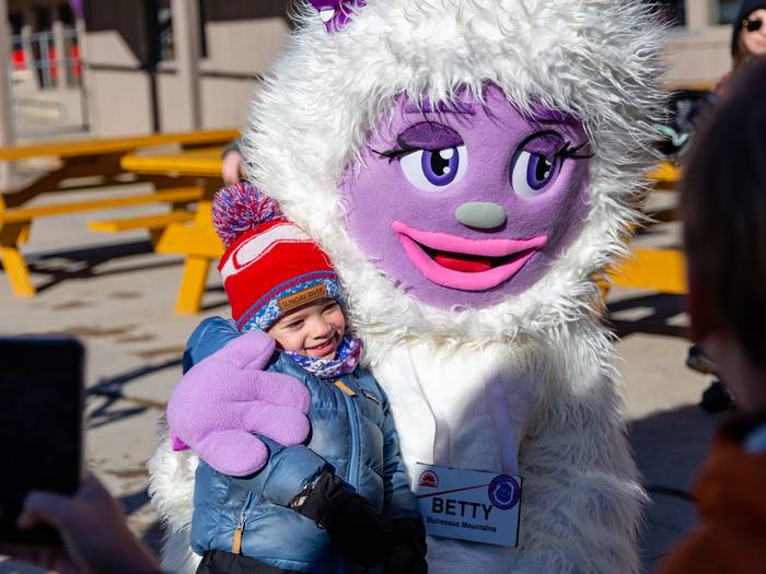 A little girl getting a hug from Betty the Yeti at Sunday River.
