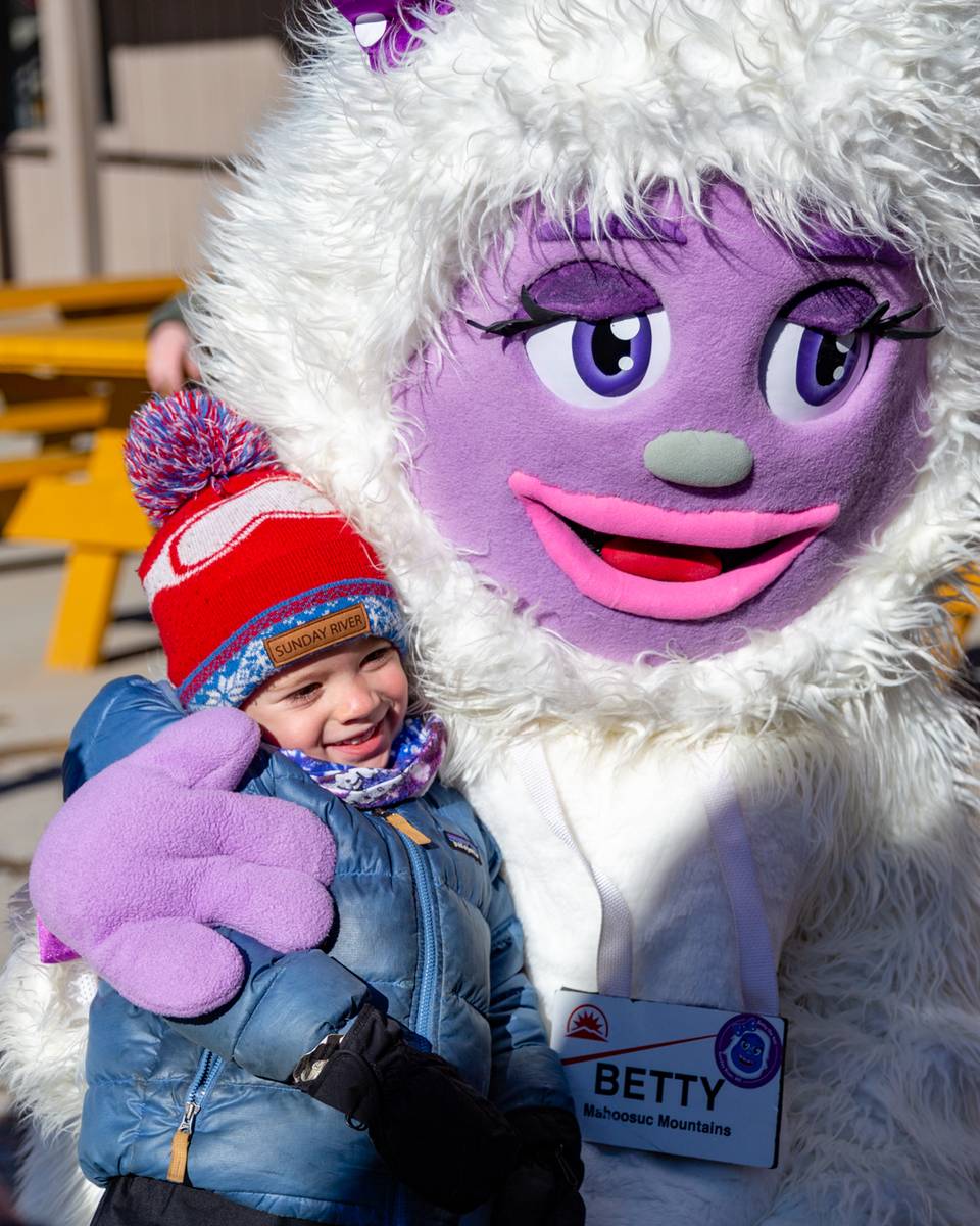 A little girl getting a hug from Betty the Yeti at Sunday River.