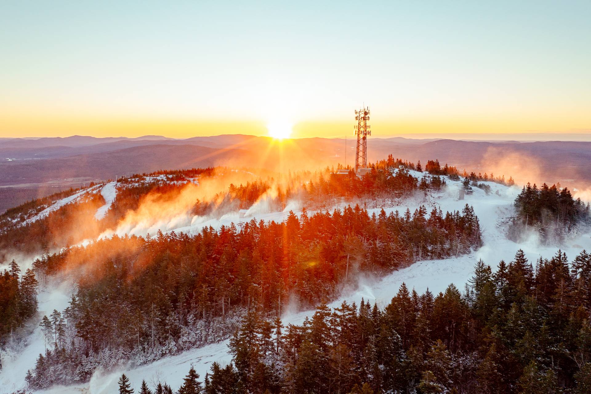 A drone view of North Peak at Sunday River Resort with blue skies and green trees.