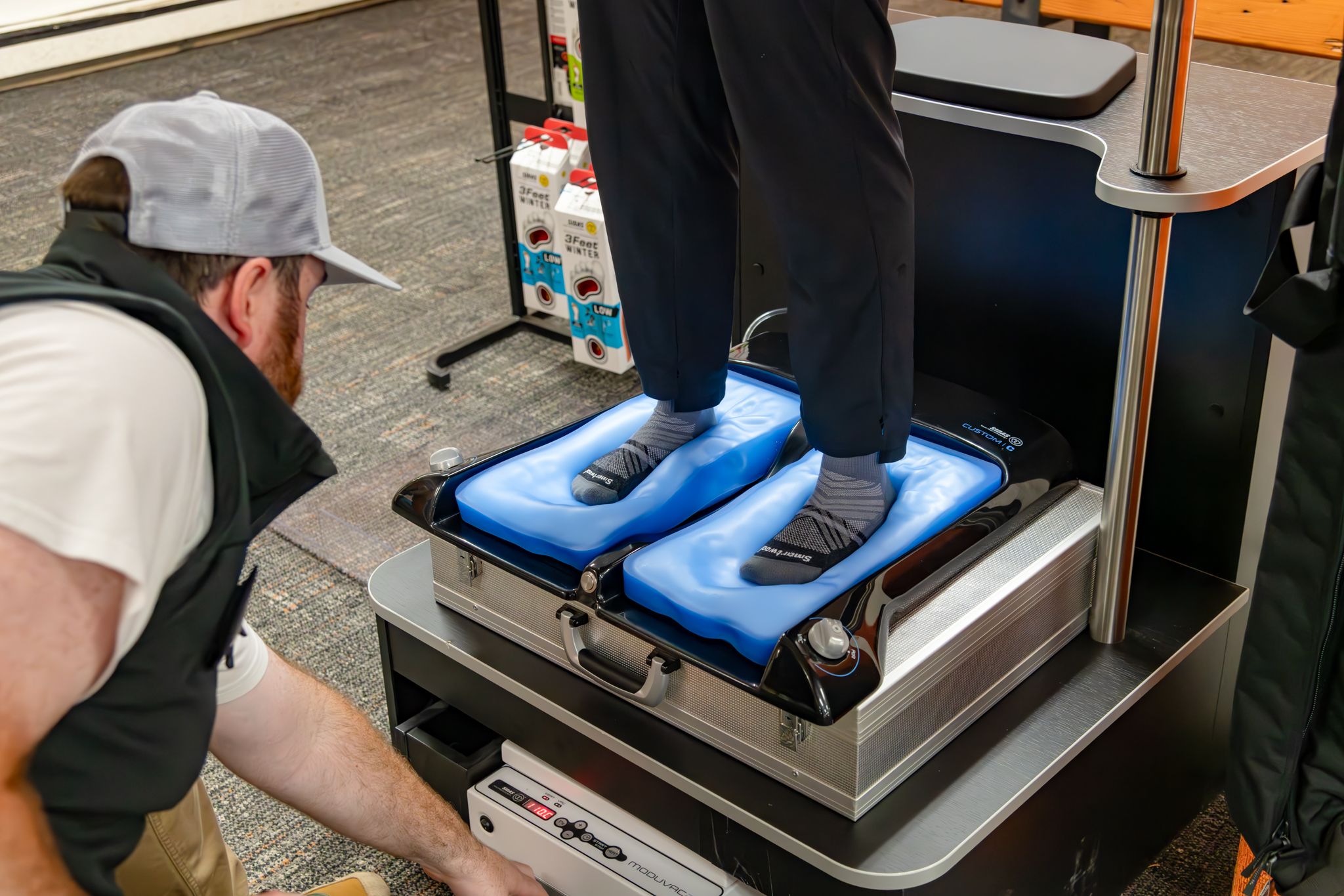 A person standing on a machine to customize their insole for the ski boots.
