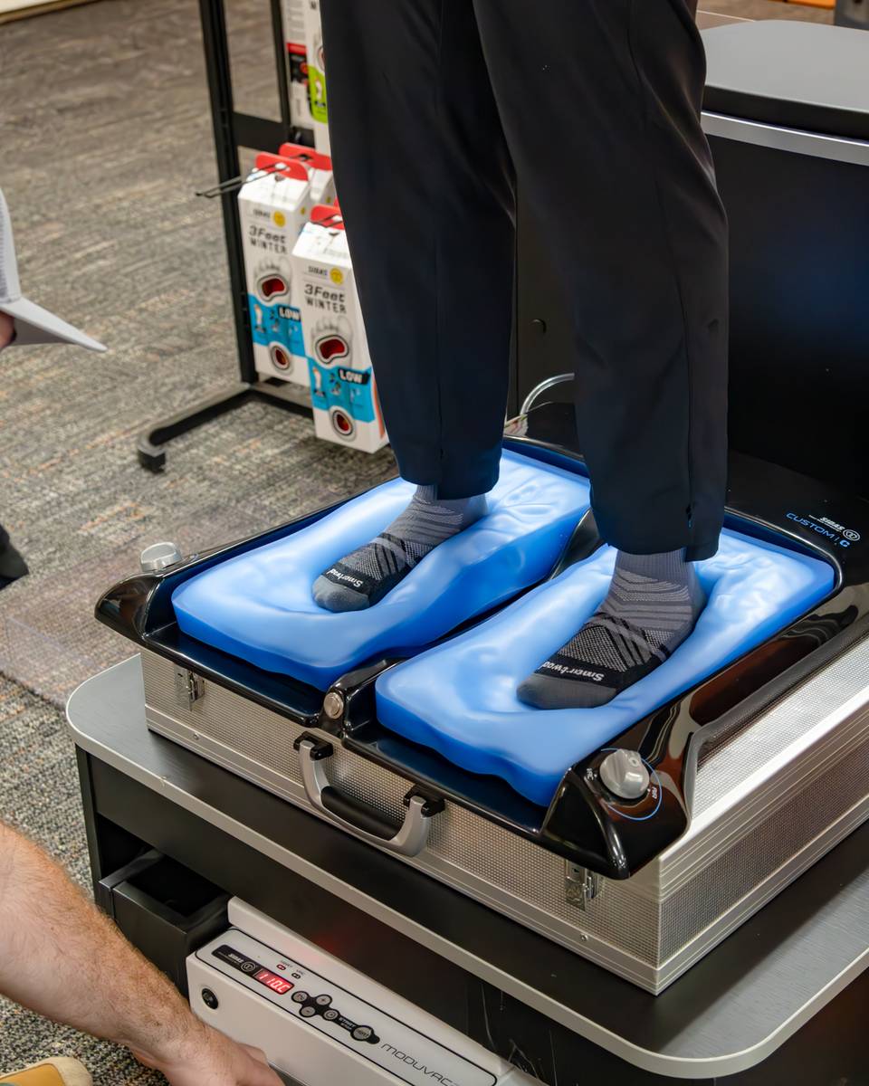 A person standing on a machine to customize their insole for the ski boots.
