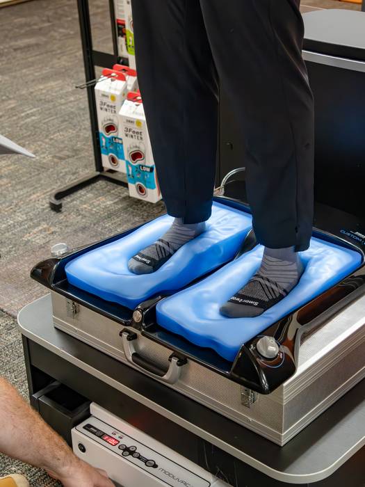 A person standing on a machine to customize their insole for the ski boots.