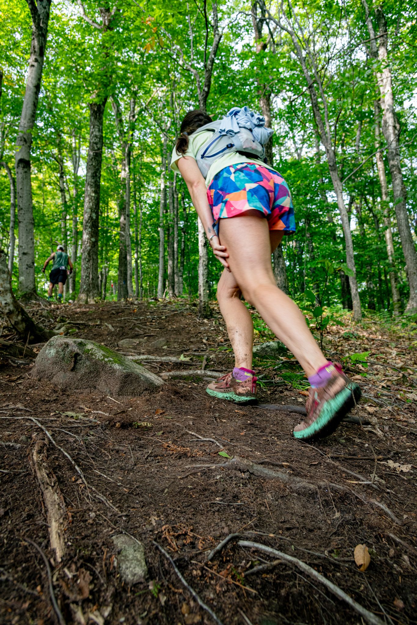 A woman hiking up a trail in the Maine woods.