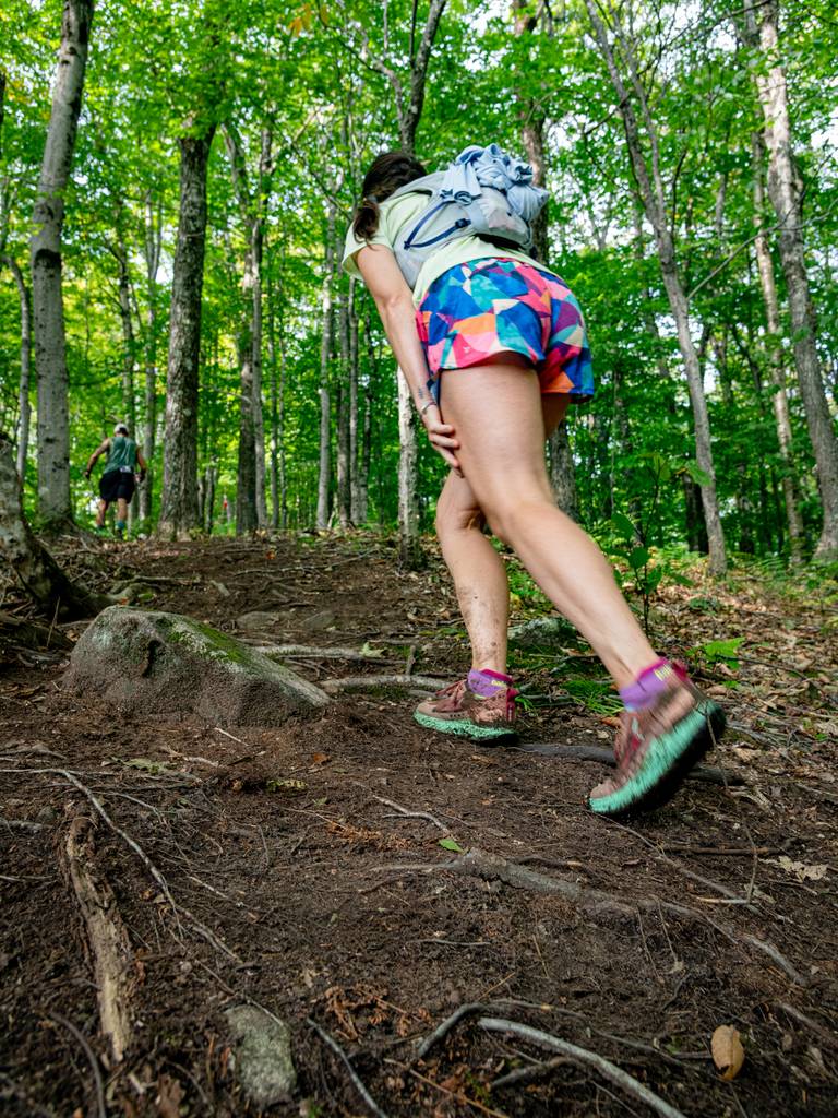 A woman hiking up a trail in the Maine woods.
