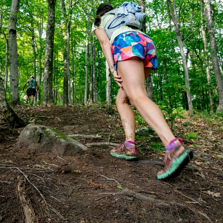 A woman hiking up a trail in the Maine woods.