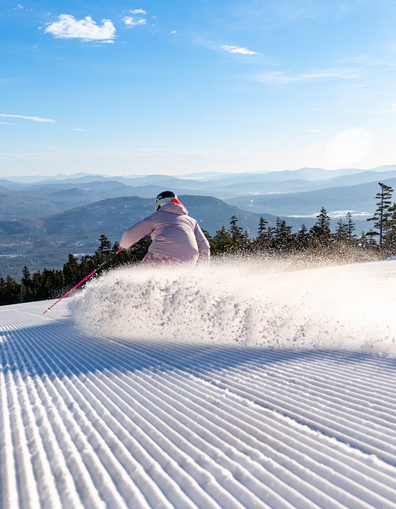 A skier carving a freshly groomed ski trail at Sunday River.
