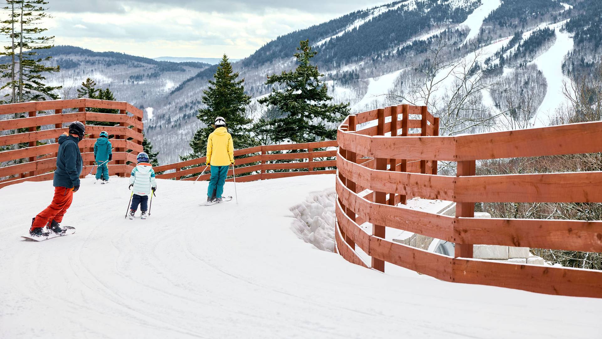 A family skiing across the bridge at Merrill Hill at Sunday River.
