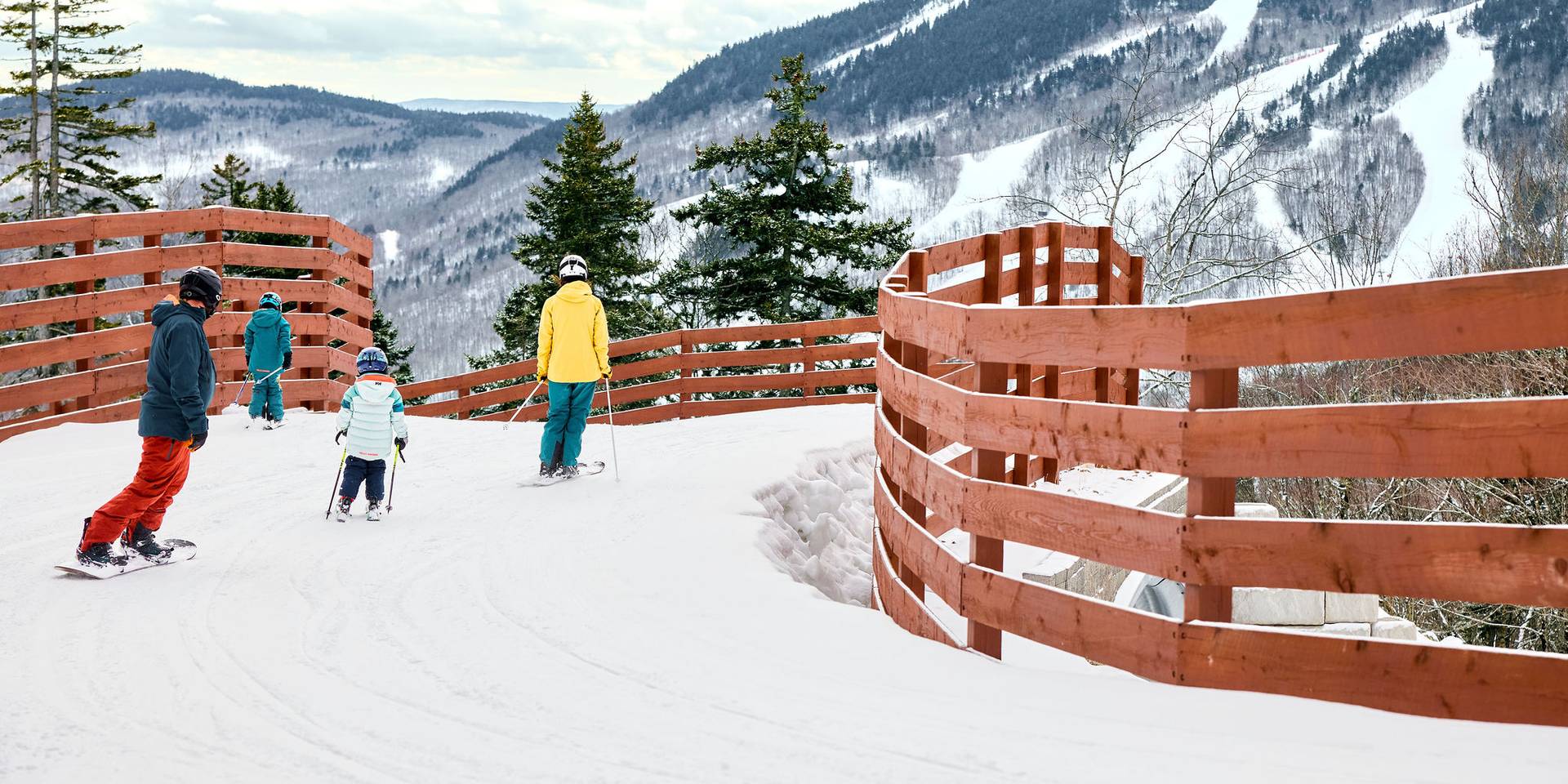 A family of skiers skiing over a bridge at Sunday River.