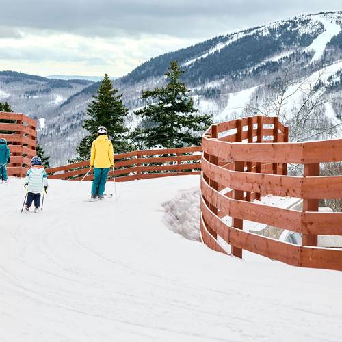 A family skiing over a bridge at Sunday River.