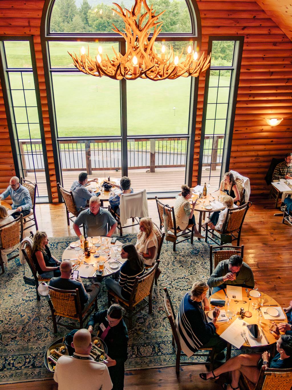Inside of The Clubhouse at Sunday River with guests enjoying a dinner in the summer.