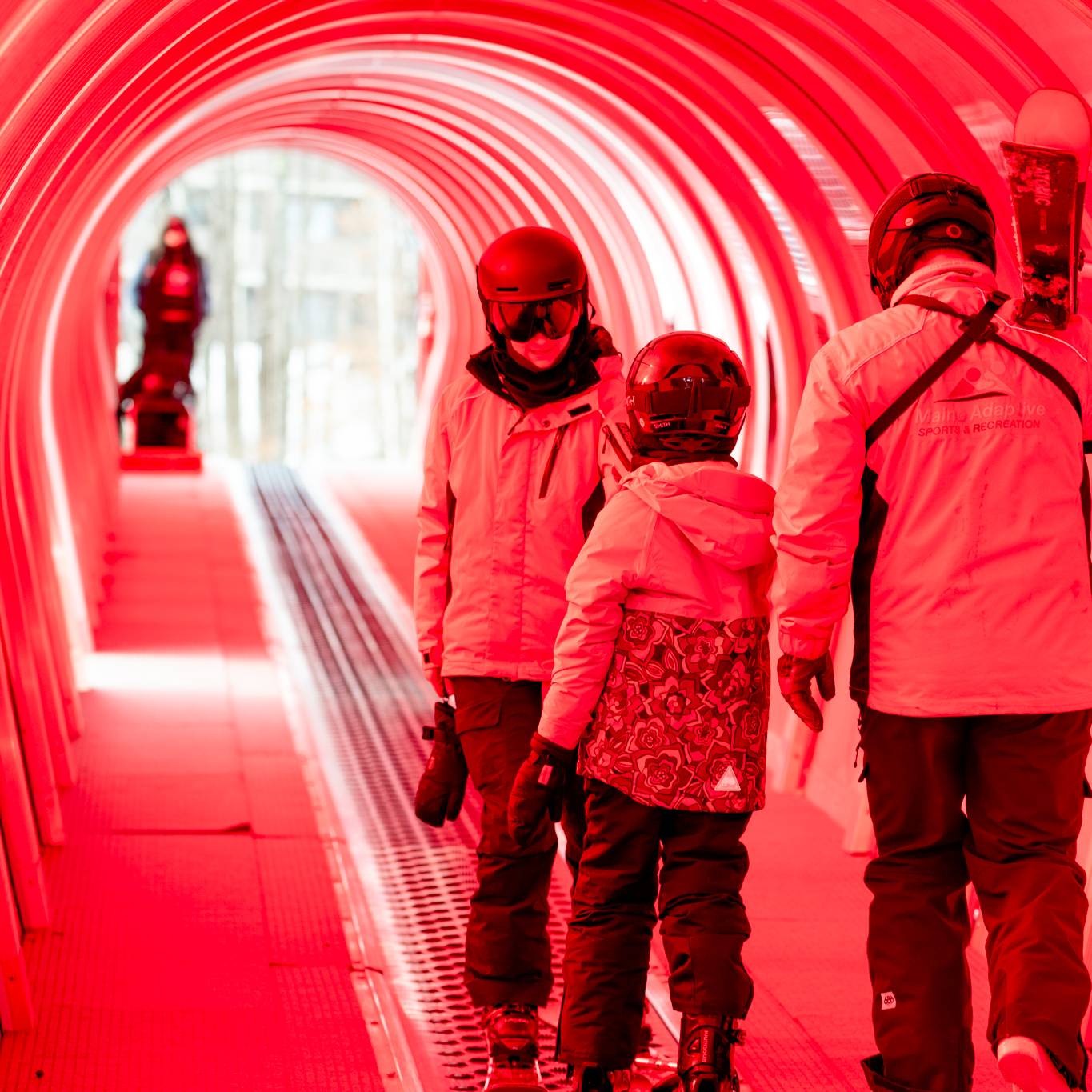A skier with her ski instructors in the magic carpet at Sunday River during their lesson.
