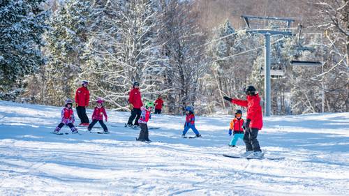A group of kids skiing with their instructor.