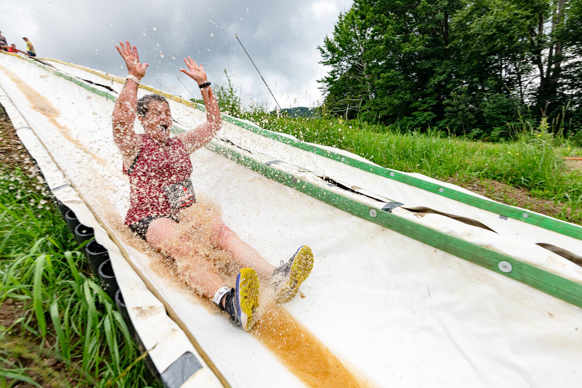 A Tough Mountain Challenge participant sliding down a waterslide.