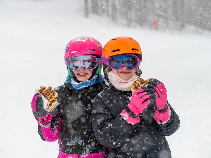 Two kids holding up chocolate covered waffles at Sunday River.